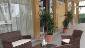 A patio area with wicker furniture and potted plants. - Hotel Capitol (Pesaro)