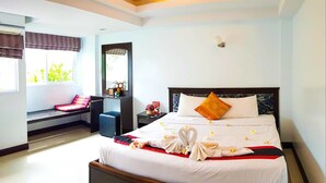 A hotel room with a large bed, a desk, a chair, and a window with curtains. - Rasta Hotel (Koh Samui)