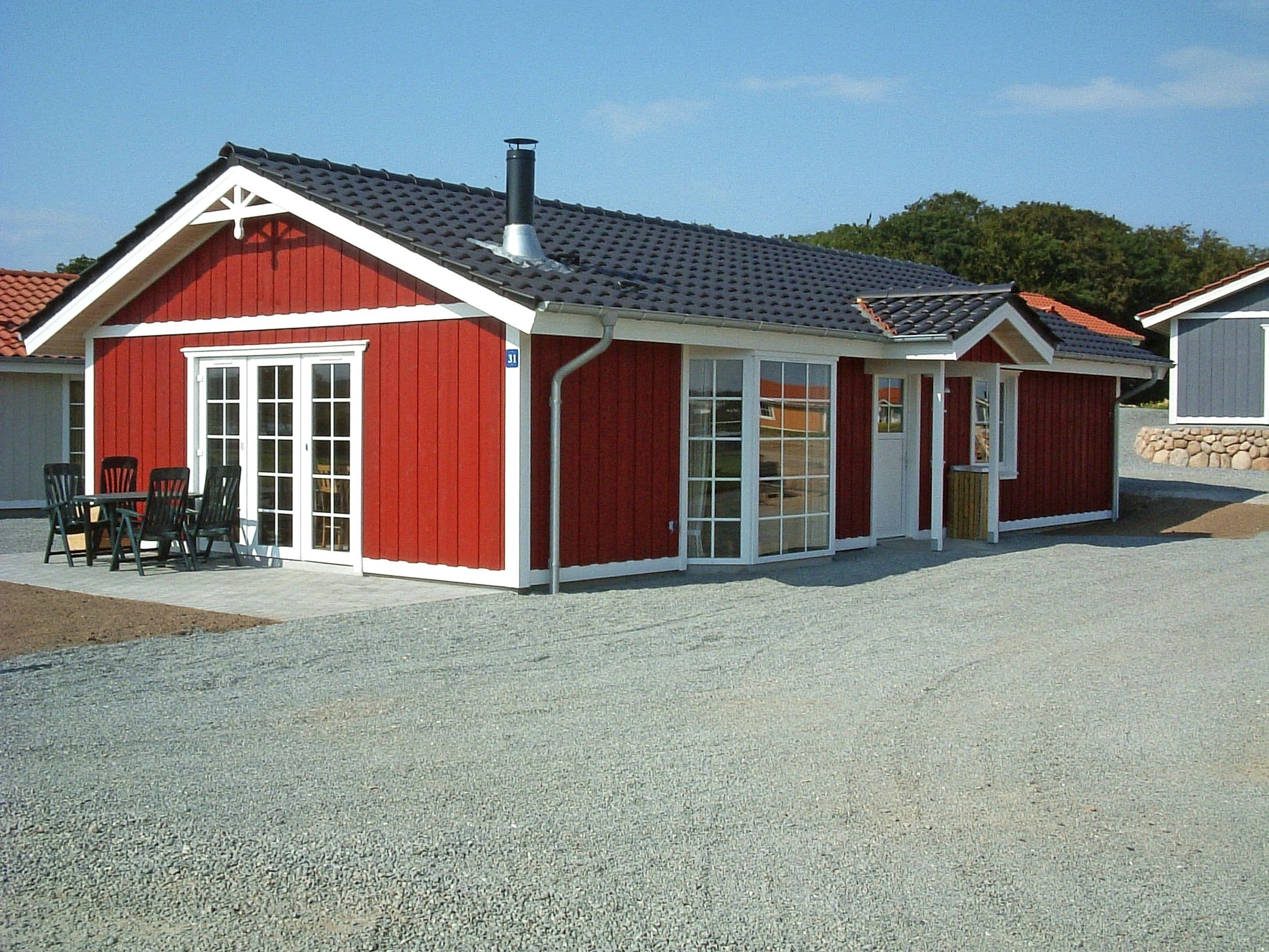 A red building with a white trim, a chimney, and a gravel driveway.