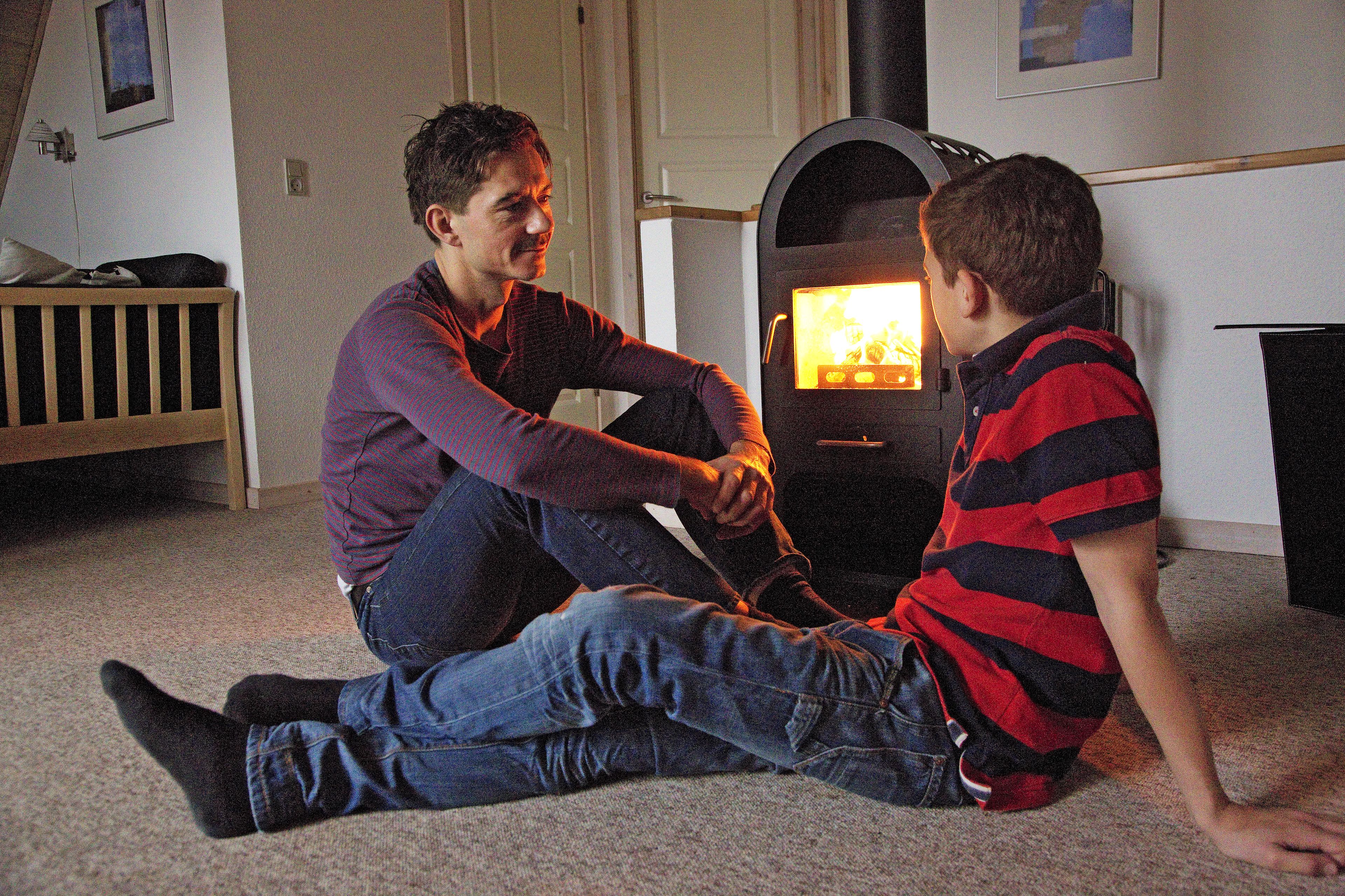 Two people sitting on the floor in a room with a fireplace.