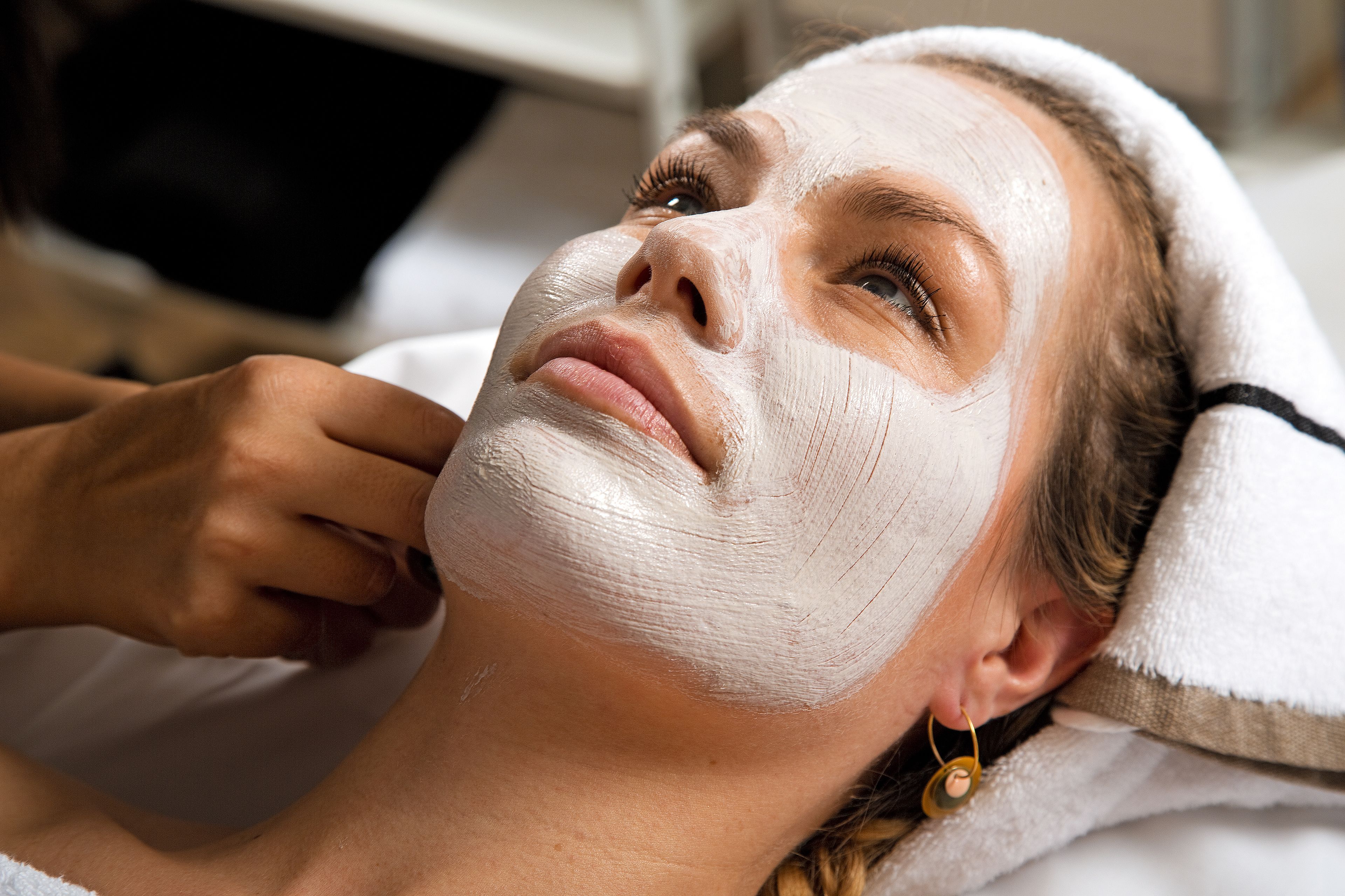 A person lying down with a towel over their head, suggesting a spa or relaxation setting.
