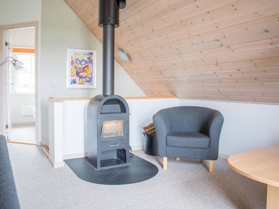 A cozy room with a modern fireplace, a comfortable armchair, and a wooden table.
