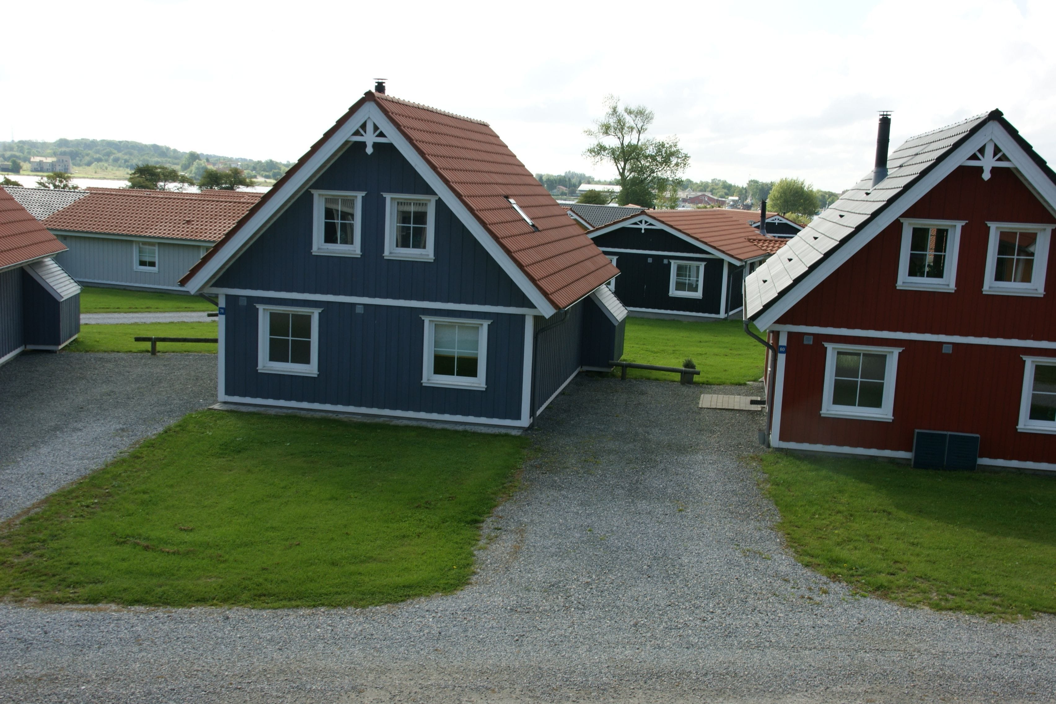 Une rangée de maisons avec une allée en gravier et des pelouses devant.