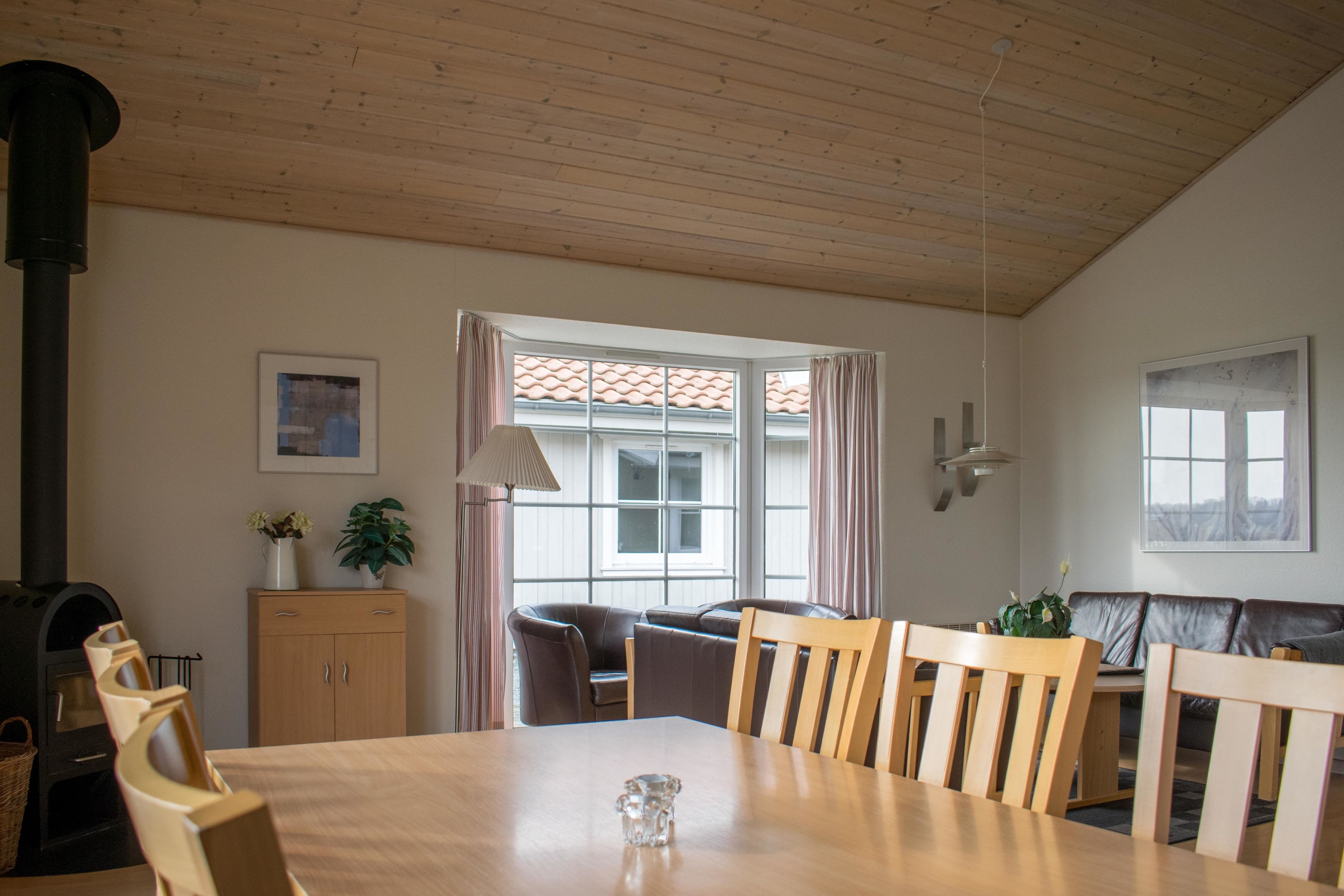 Ein Essbereich mit Holztisch, Stühlen, einer Couch, einem Kamin und einem Fenster mit Vorhängen.