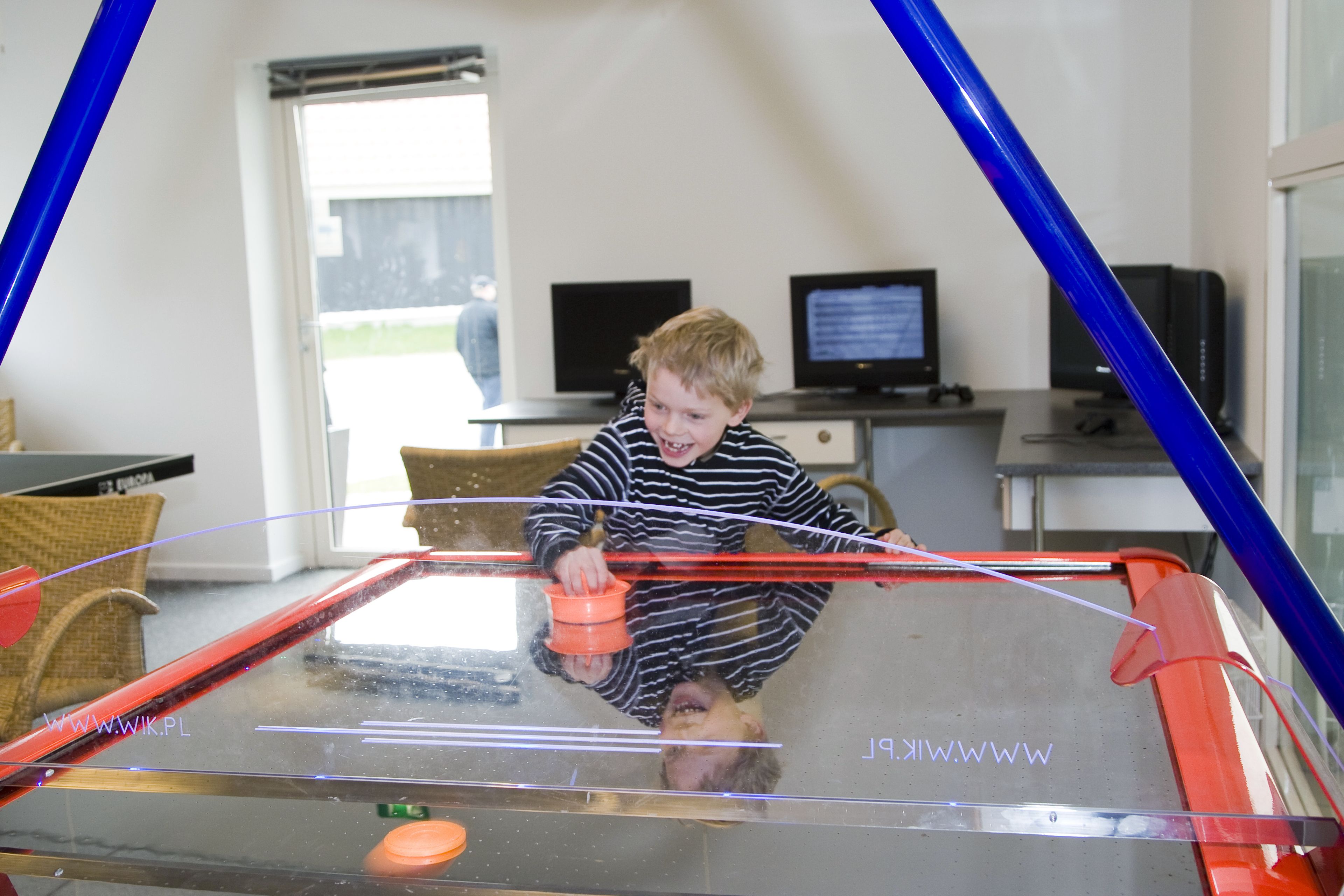 A child playing with a toy car inside a glass enclosure.