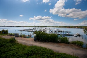 A marina with boats docked, surrounded by greenery and a clear sky.