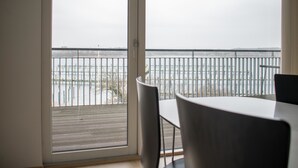 A room with a view of a body of water through a balcony with a metal railing. - Enjoy Resorts Marina Fiskenæs (Grasten)