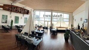 A spacious restaurant with high ceilings, large windows, and a variety of seating arrangements including tables and chairs. - Enjoy Resorts Marina Fiskenæs (Grasten)