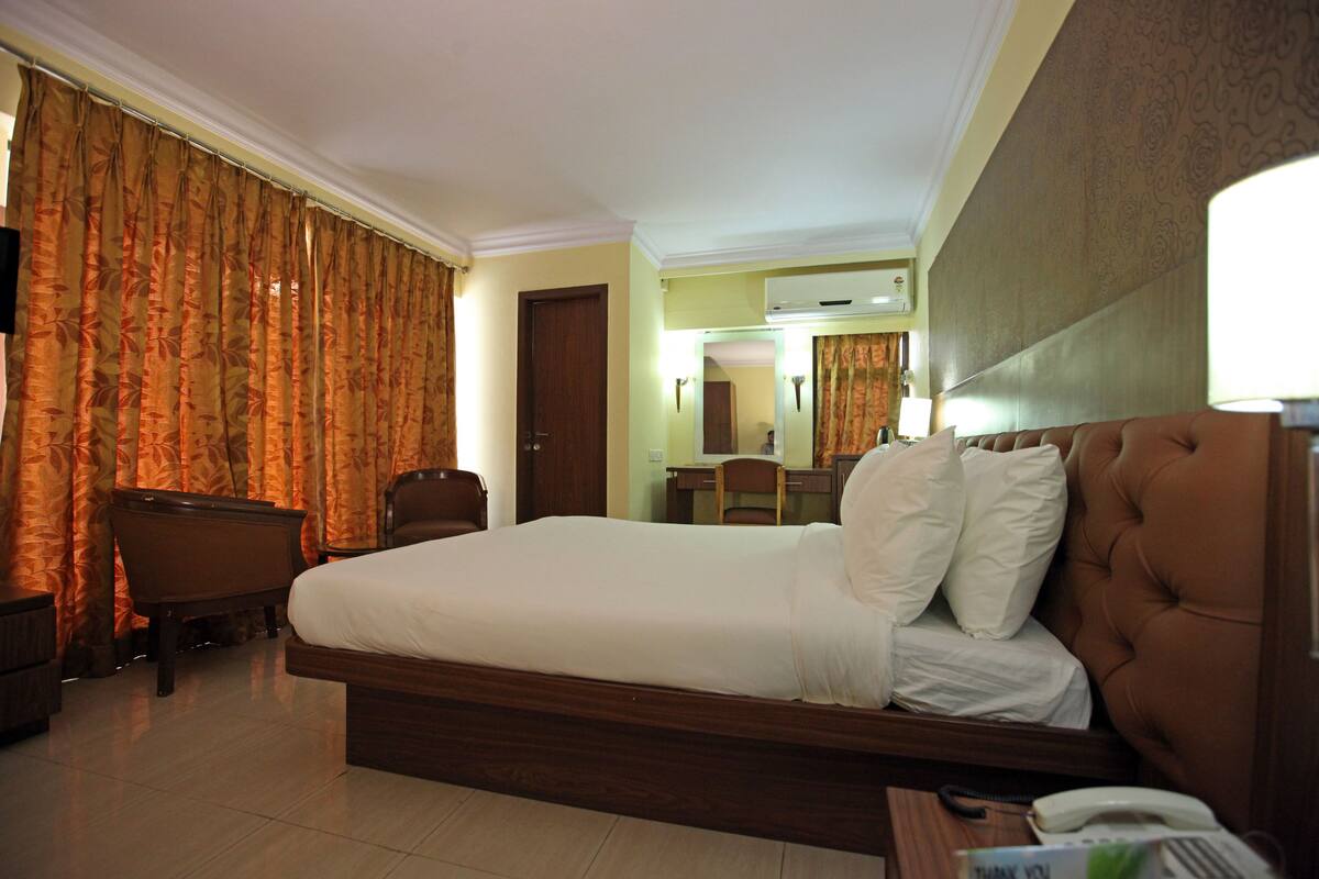 A hotel room with a large bed, a desk, a chair, and a bathroom.