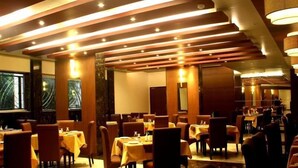 Un restaurante con varias mesas y sillas, iluminación cálida y un diseño interior moderno.