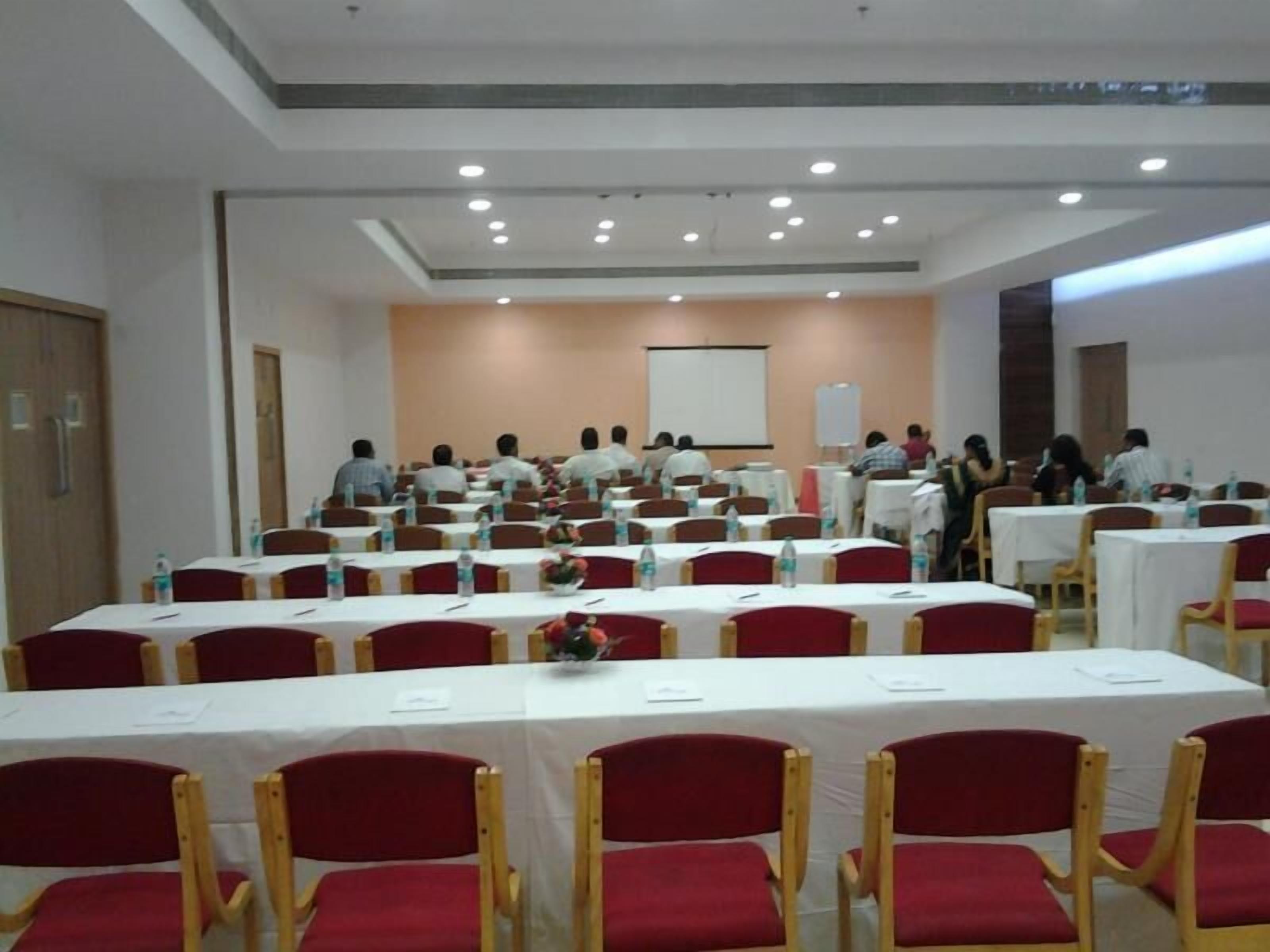 Un salón de conferencias con filas de mesas y sillas, equipado con botellas de agua y tarjetas de identificación.