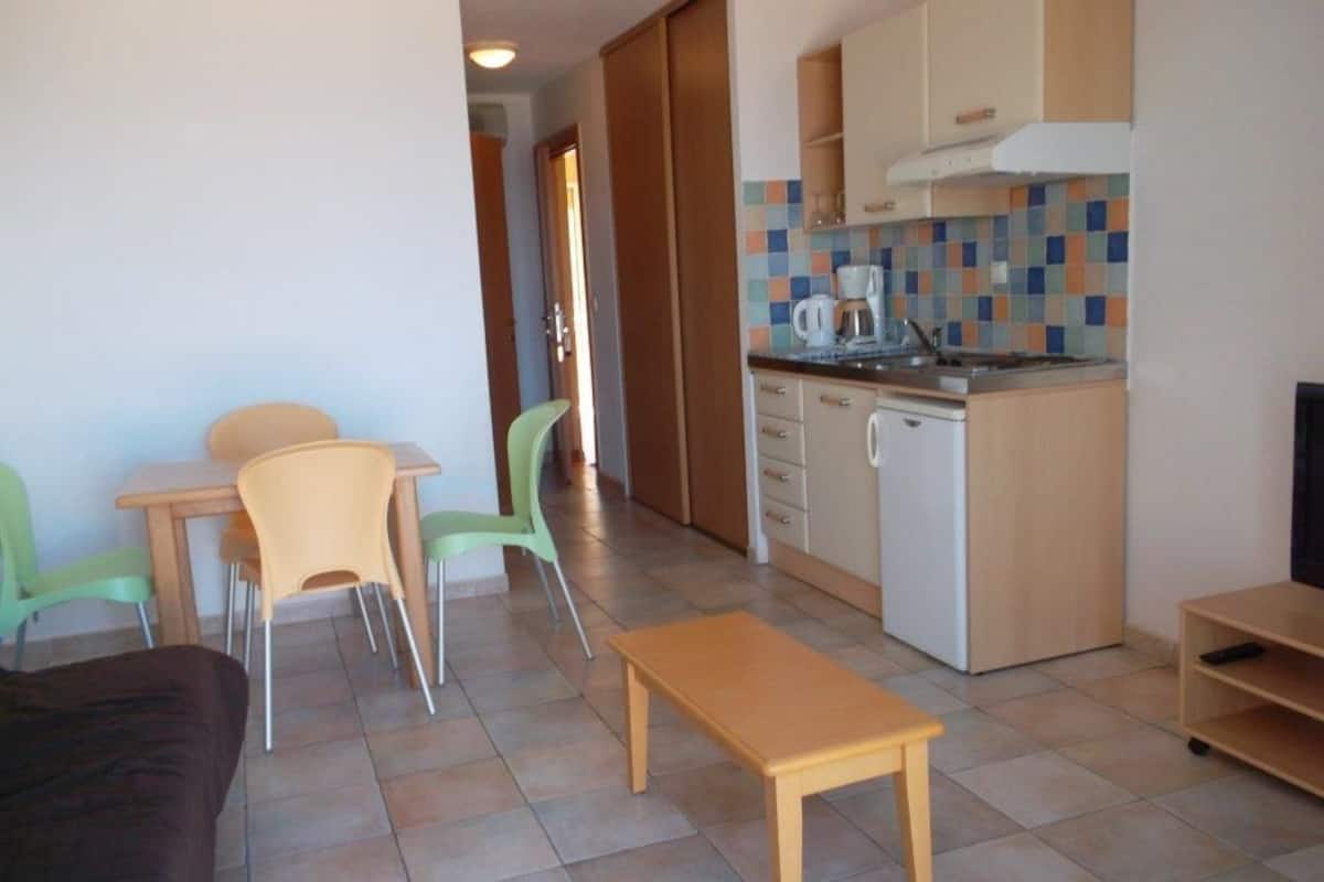 Un espace de vie compact comprenant un coin repas, une kitchenette et un petit coin salon.