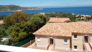 A coastal property with terracotta tiled roofs, a balcony, and a view of the sea.