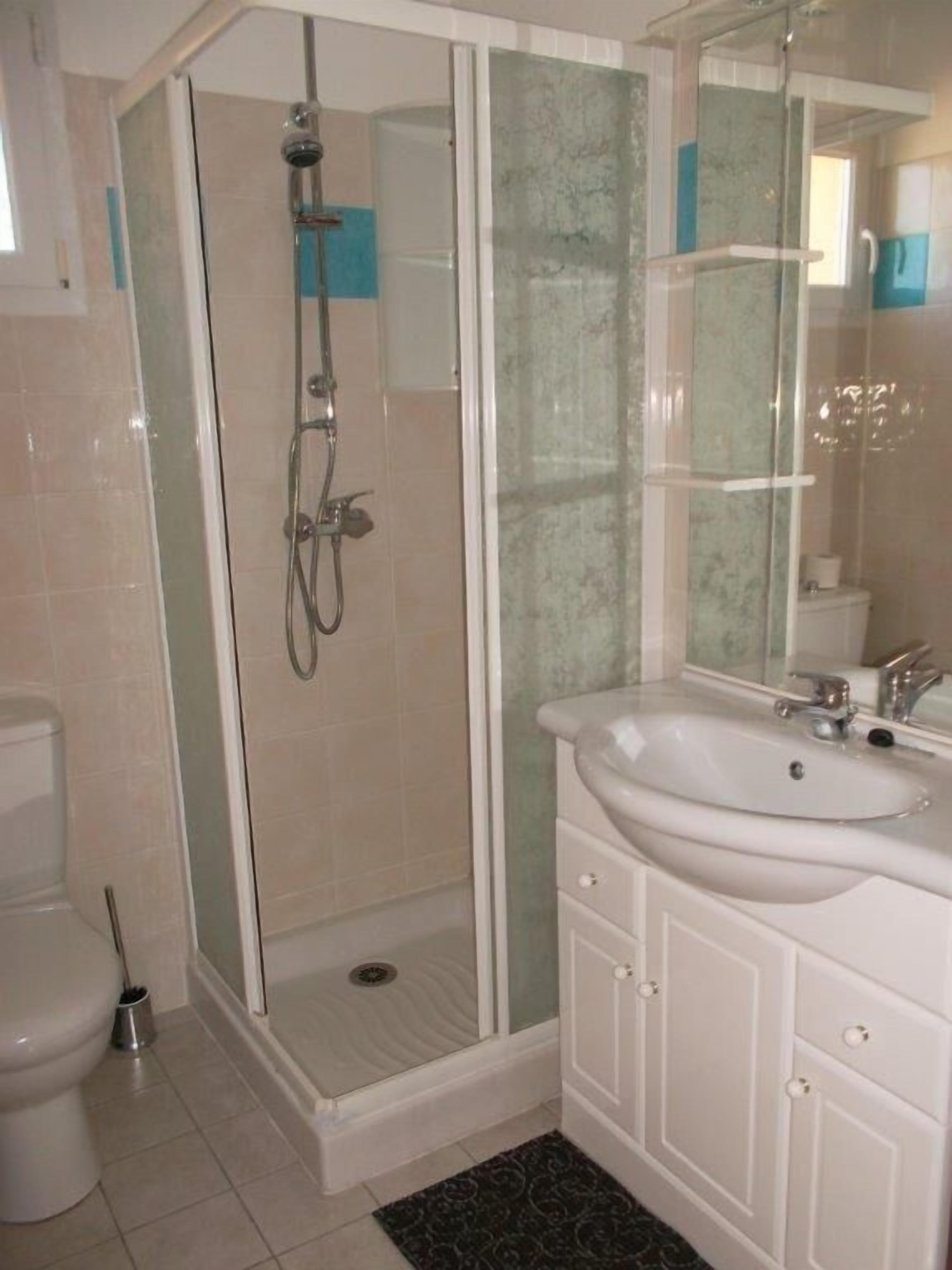 A bathroom with a glass-enclosed shower, a white sink, and a mirror above it.