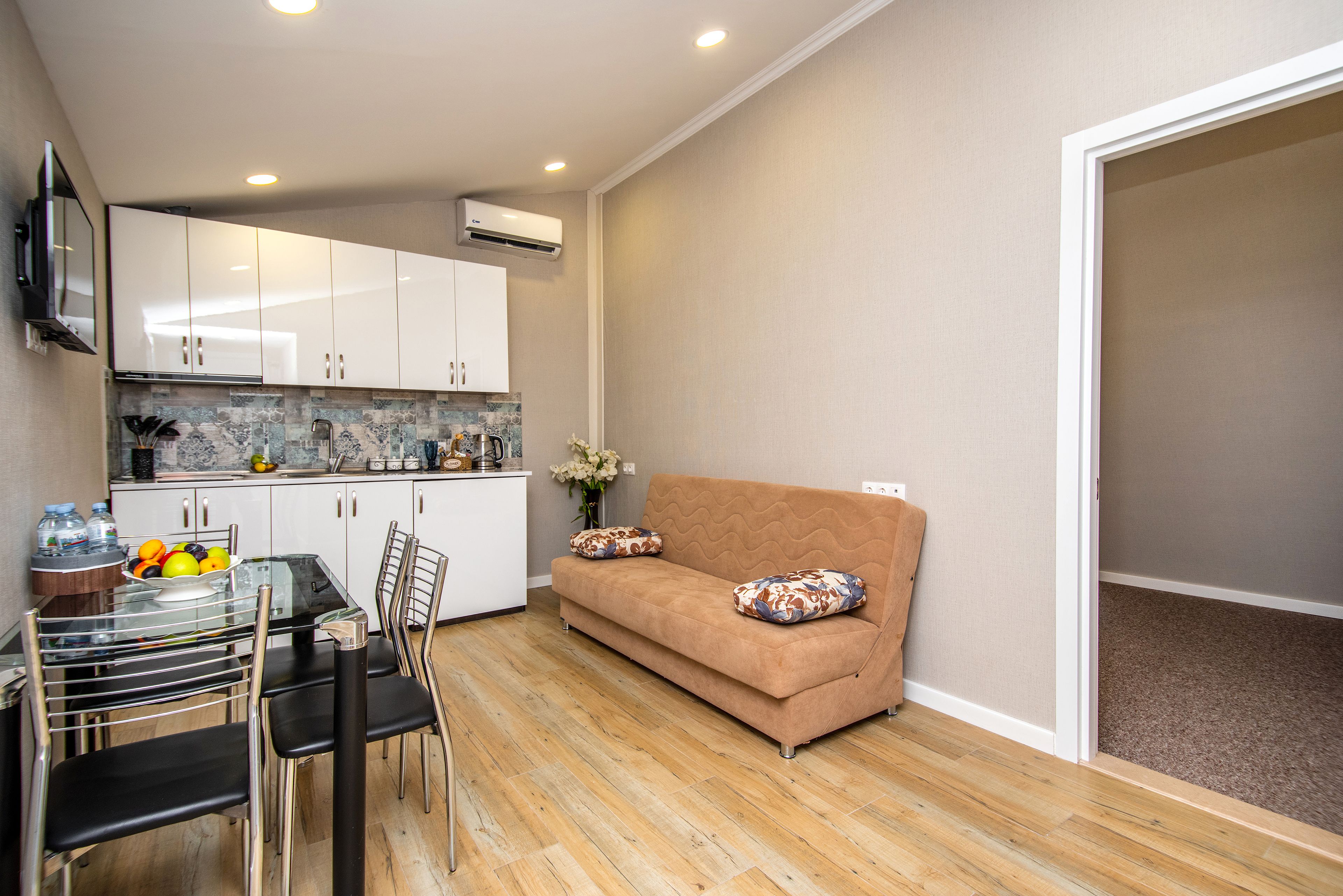 A compact living space with a kitchenette, a dining area, and a sofa with decorative pillows.