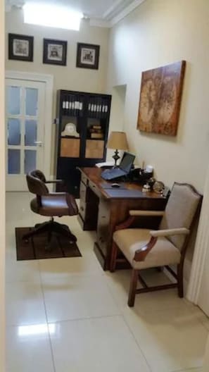 Une pièce comprenant un bureau, deux chaises, une bibliothèque et une porte.