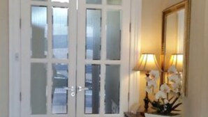 A hallway with a double door, a chandelier, a lamp, and a sofa.