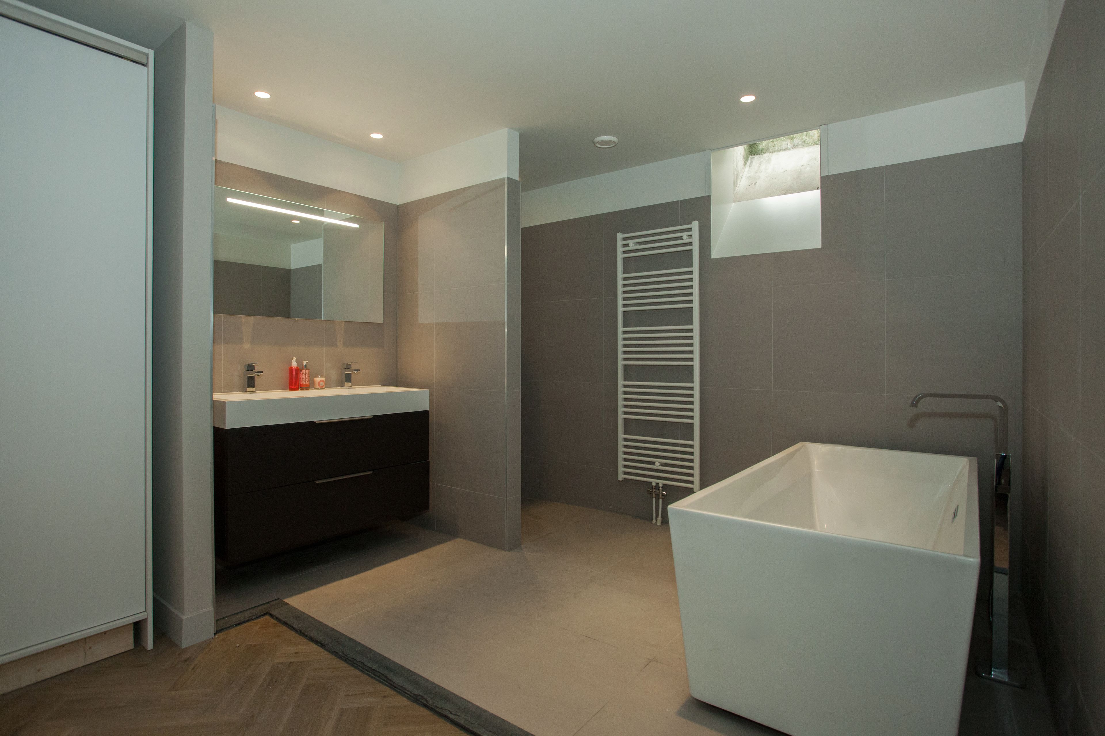 A modern bathroom with a large bathtub, a double sink vanity, and a walk-in shower.