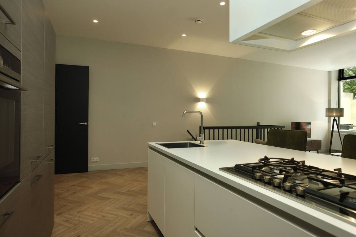 Une cuisine moderne dotée d’un îlot central, d’une cuisinière intégrée et d’une porte noire.
