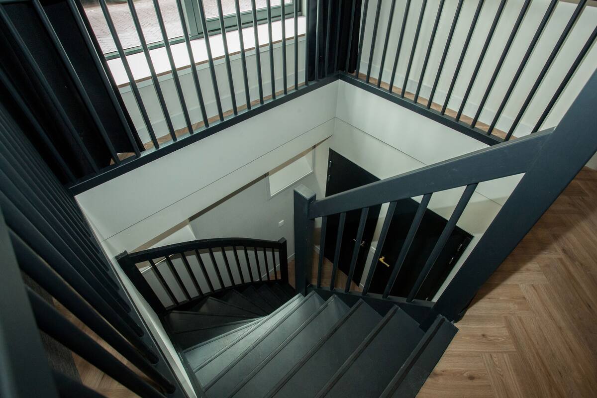 Un intérieur moderne avec un escalier en colimaçon et des rampes noires.