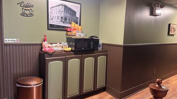 A hotel lobby with a no-smoking sign, a coffee station, a microwave, and a framed picture on the wall.
