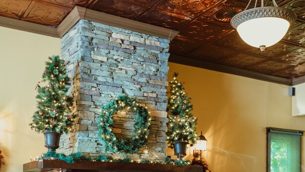 A dining area with a stone fireplace, wooden chairs, and tables covered with pink tablecloths. - The Hotel Belvidere (Hawley)
