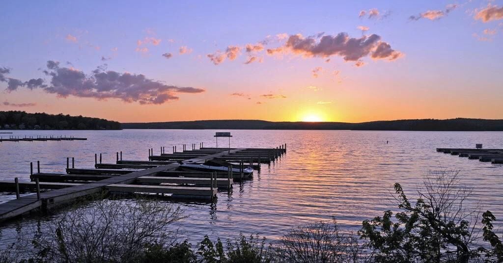 Un coucher de soleil sur un lac paisible, avec des quais qui s’avancent dans l’eau.