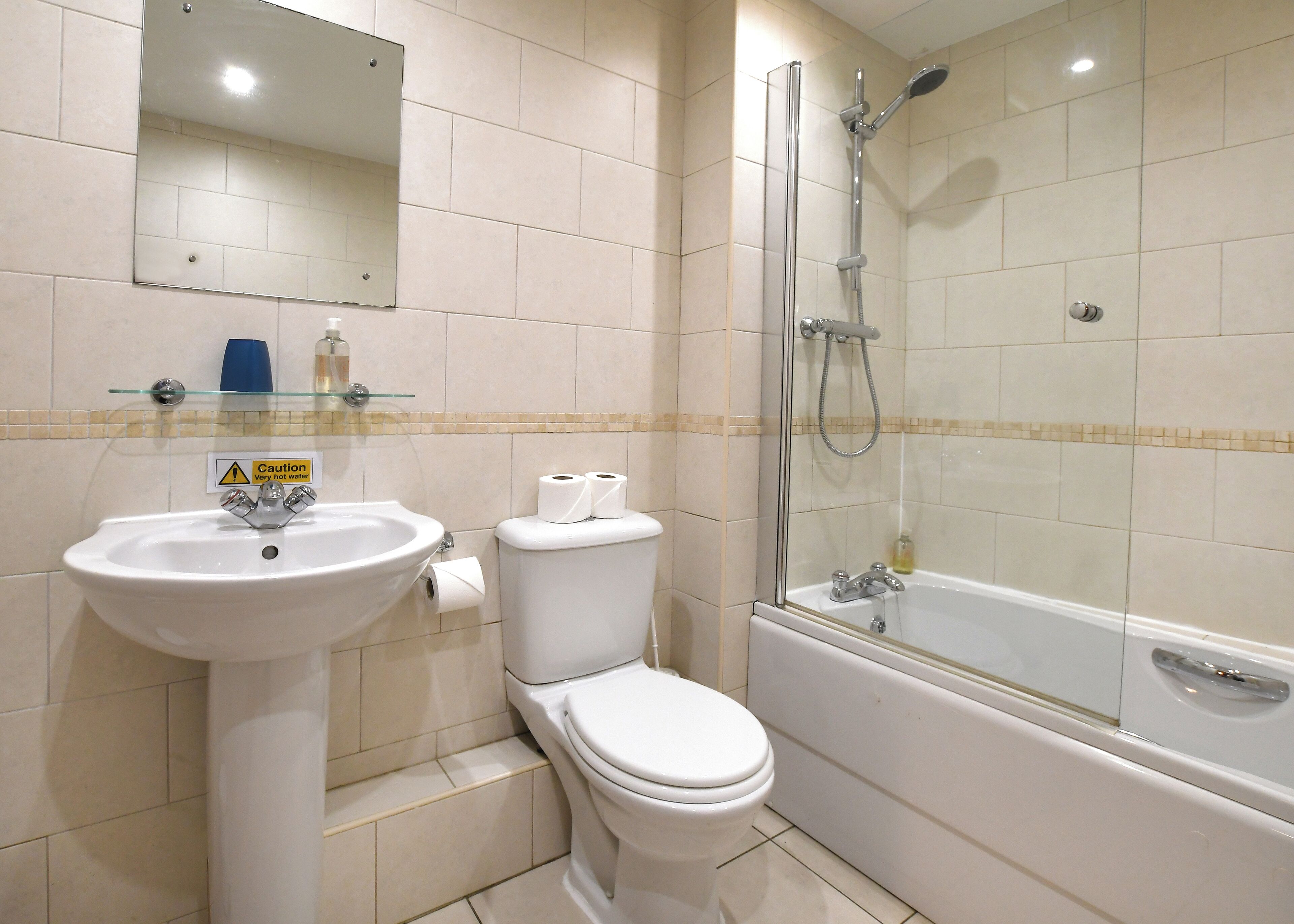 Un baño con lavamanos, inodoro y zona de ducha con mampara de vidrio.