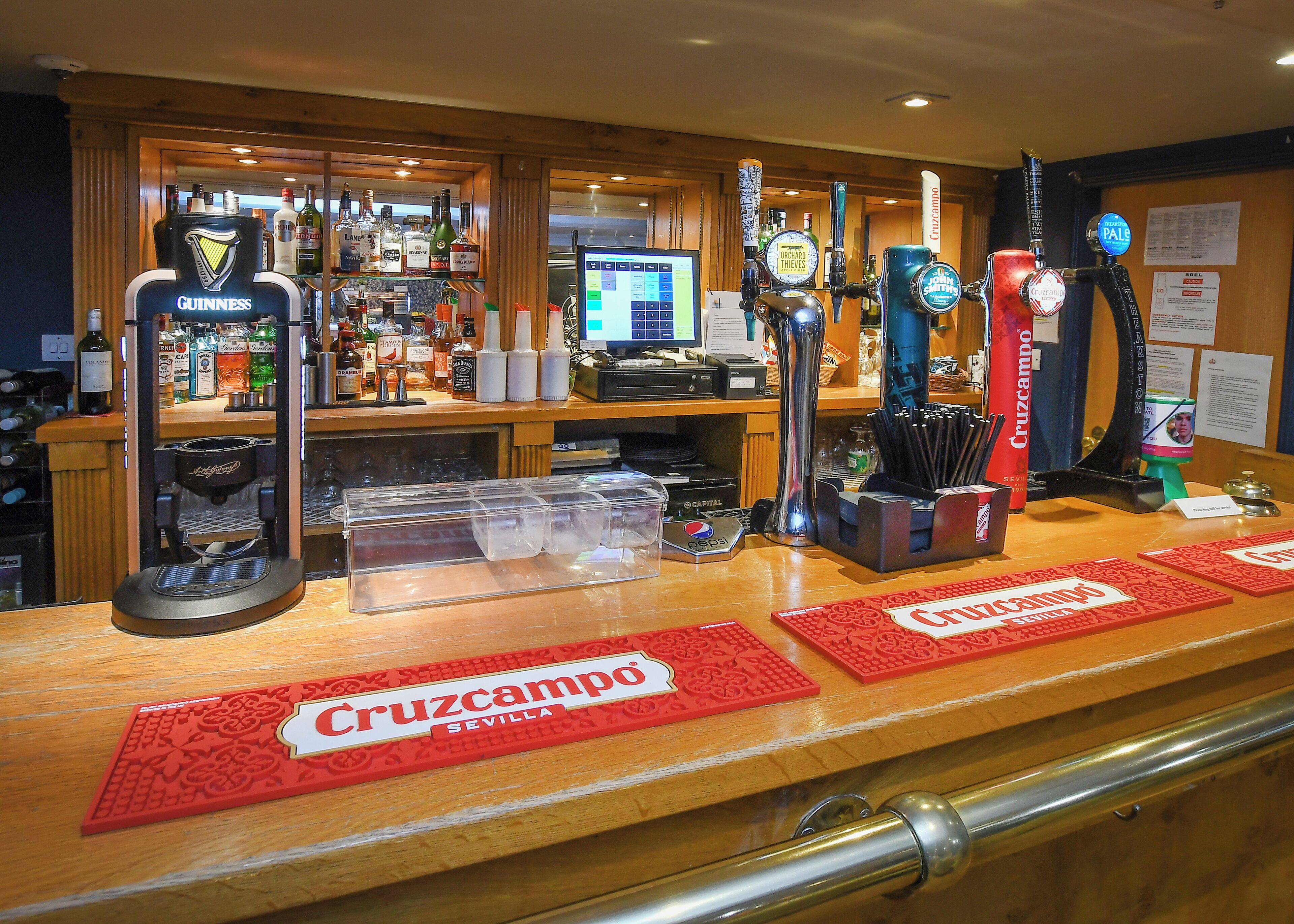 A bar area with multiple beer taps, a cash register, and a computer monitor.