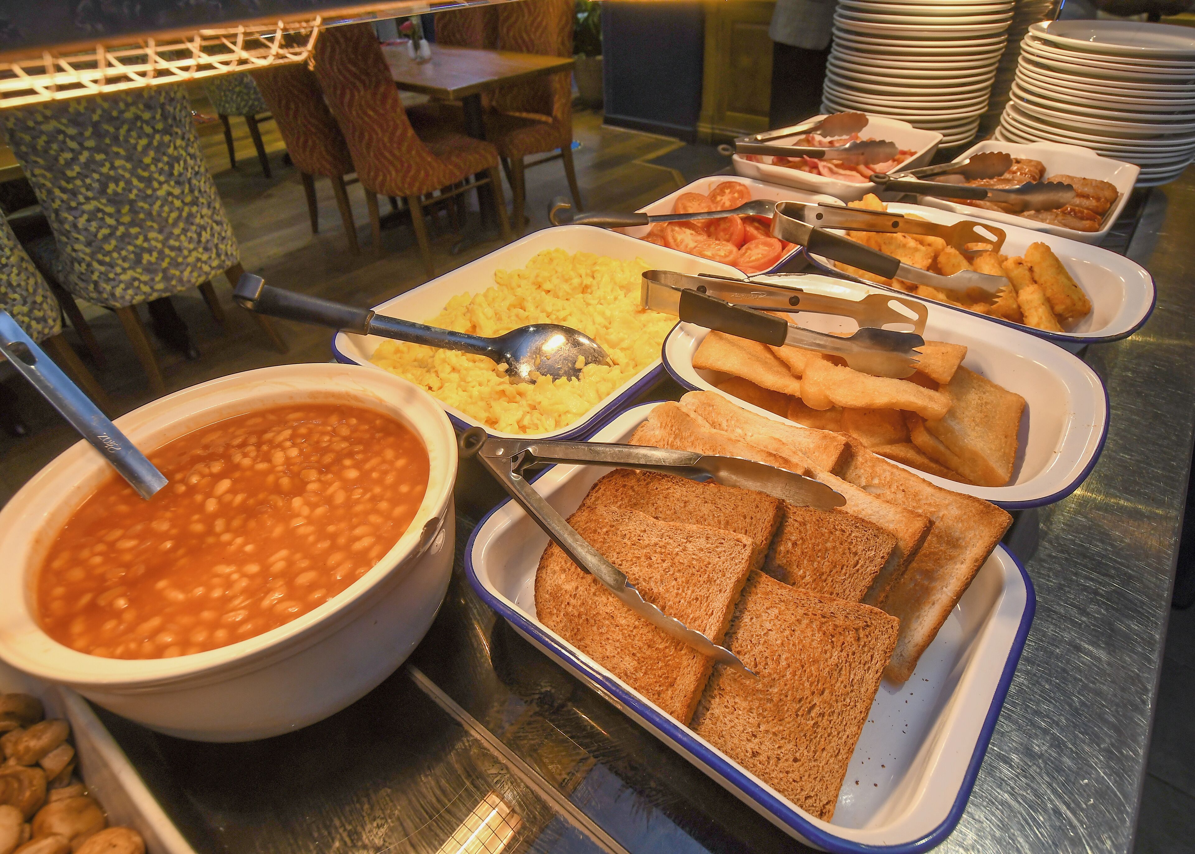 A buffet with various food items including beans, rice, toast, and other dishes.