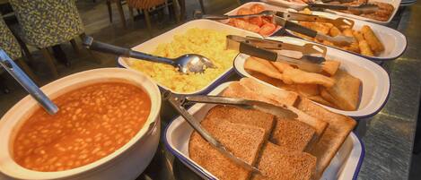 A buffet with various food items including beans, rice, toast, and other dishes.