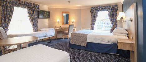 A hotel room with two beds, a desk, a chair, and a small table.
