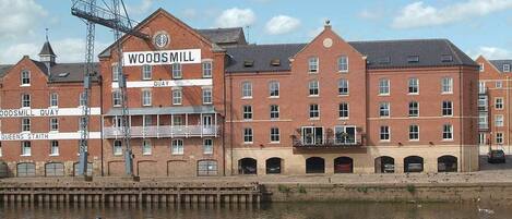 A large brick building with multiple windows and a sign reading "WOODS MILL QUAY."