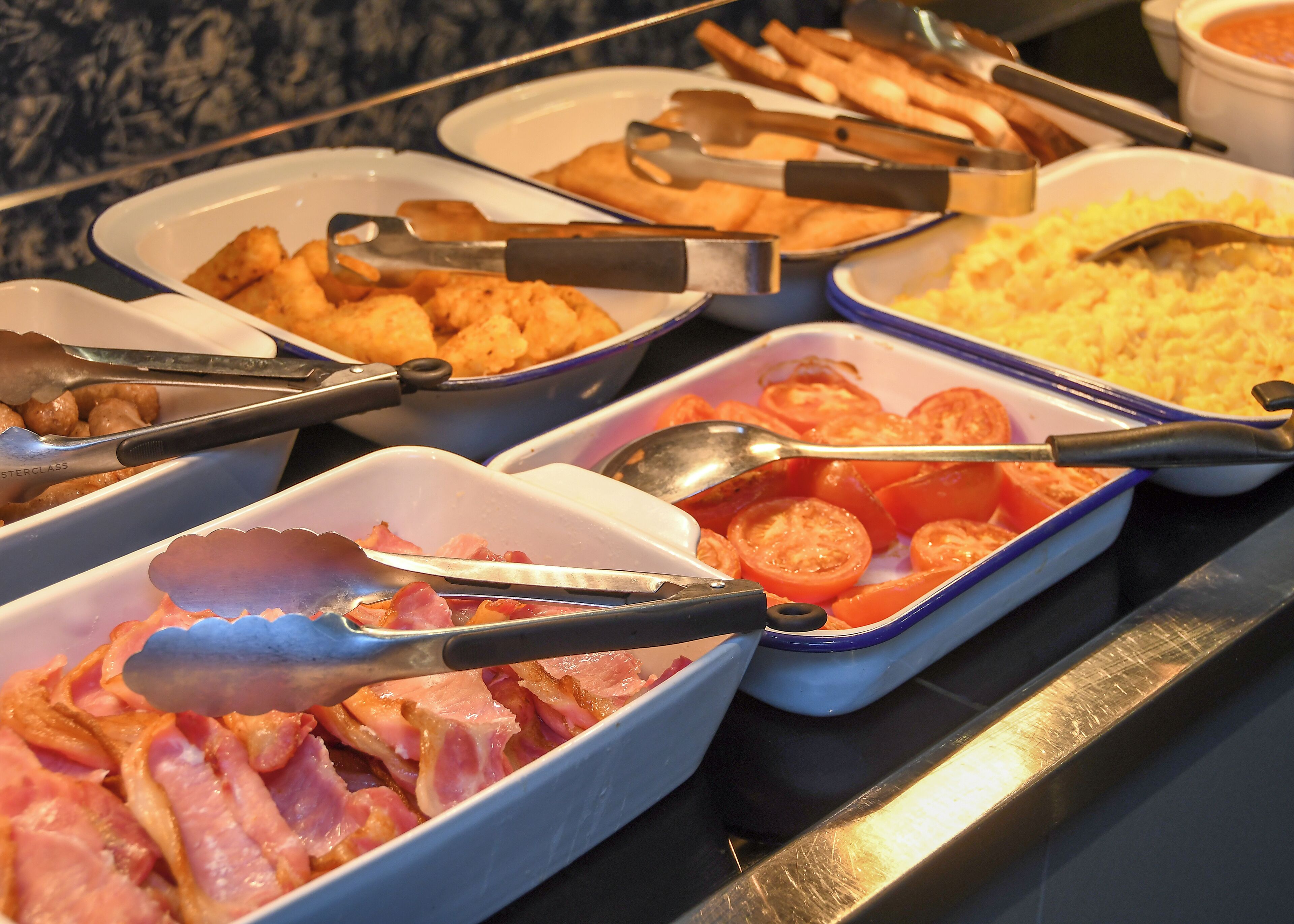 A buffet with various food items including ham, tomatoes, and other dishes.