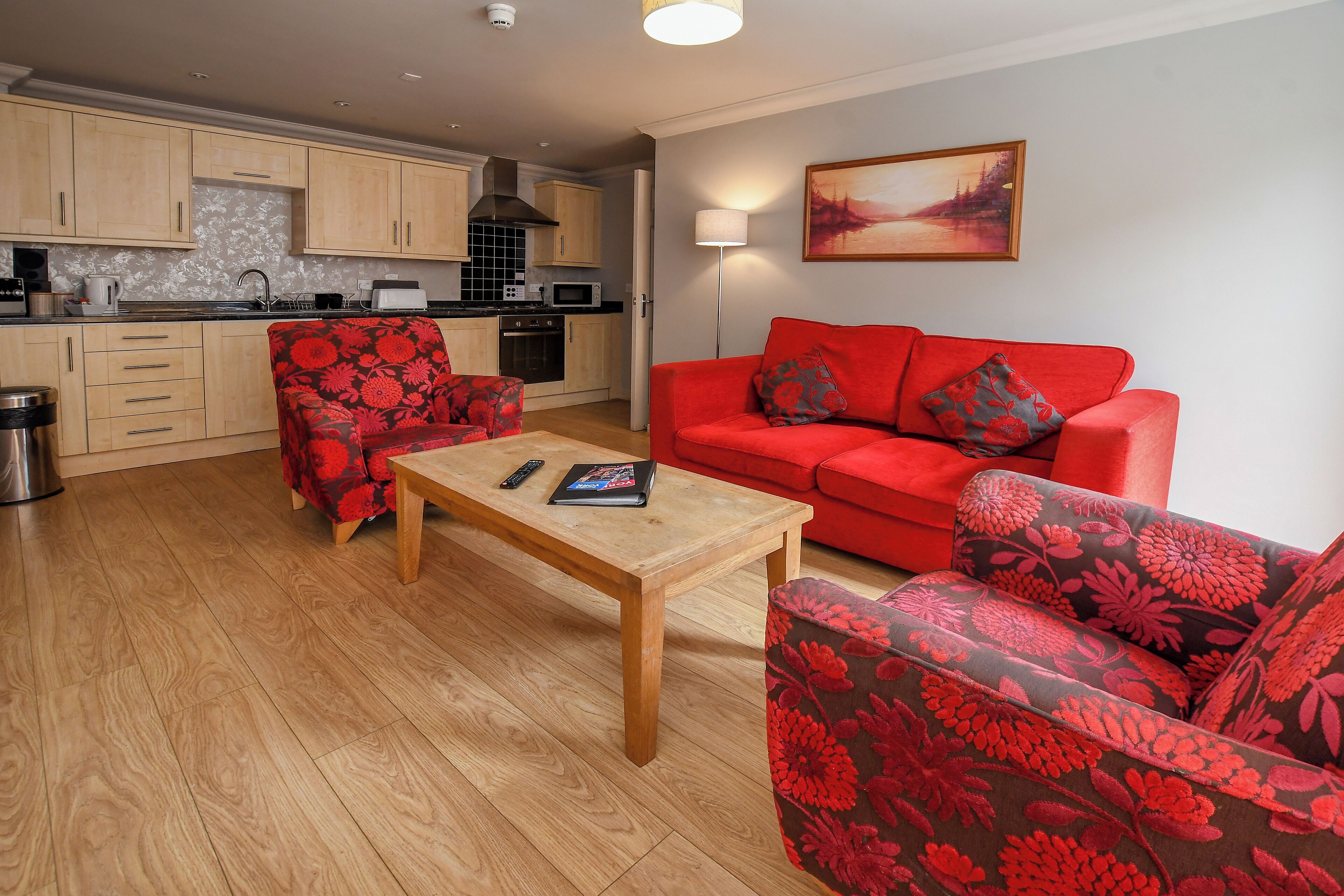 Ein Wohnzimmer mit einem roten Sofa, einem passenden Sessel und einem Holztisch.