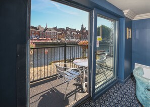 A balcony with a table and chairs, a view of a river, and buildings in the background. - The Queens Hotel & Victoria Cloisters (York)