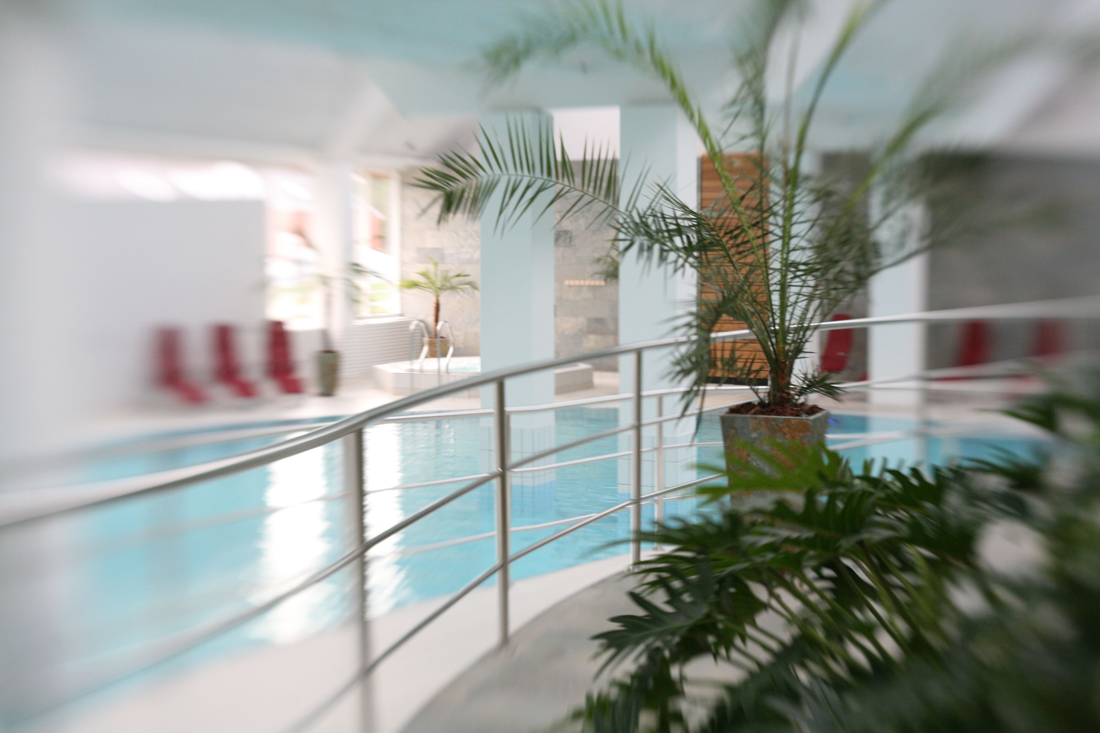 An indoor swimming pool with a clear view of the water, surrounded by a metal railing.
