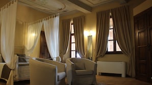 A bedroom with a four-poster bed, two armchairs, a nightstand, and a radiator. - Dimora Cortese (Castagnole delle Lanze)