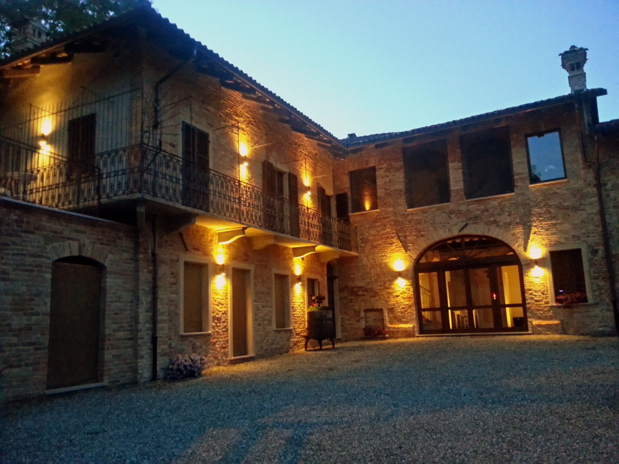 Edificio de piedra con patio central, que presenta una entrada abovedada grande y varios balcones con iluminación.
