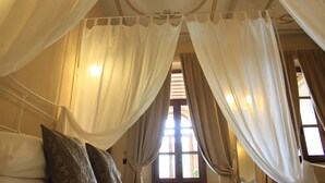 A room with a canopy bed, a window with curtains, and a floral ceiling design. - Dimora Cortese (Castagnole delle Lanze)