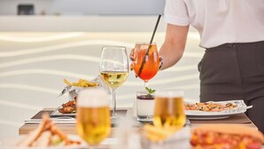 A dining table with various dishes and drinks, including a pizza, fries, and a cocktail. - Welikehotel Fenix (Llucmajor)