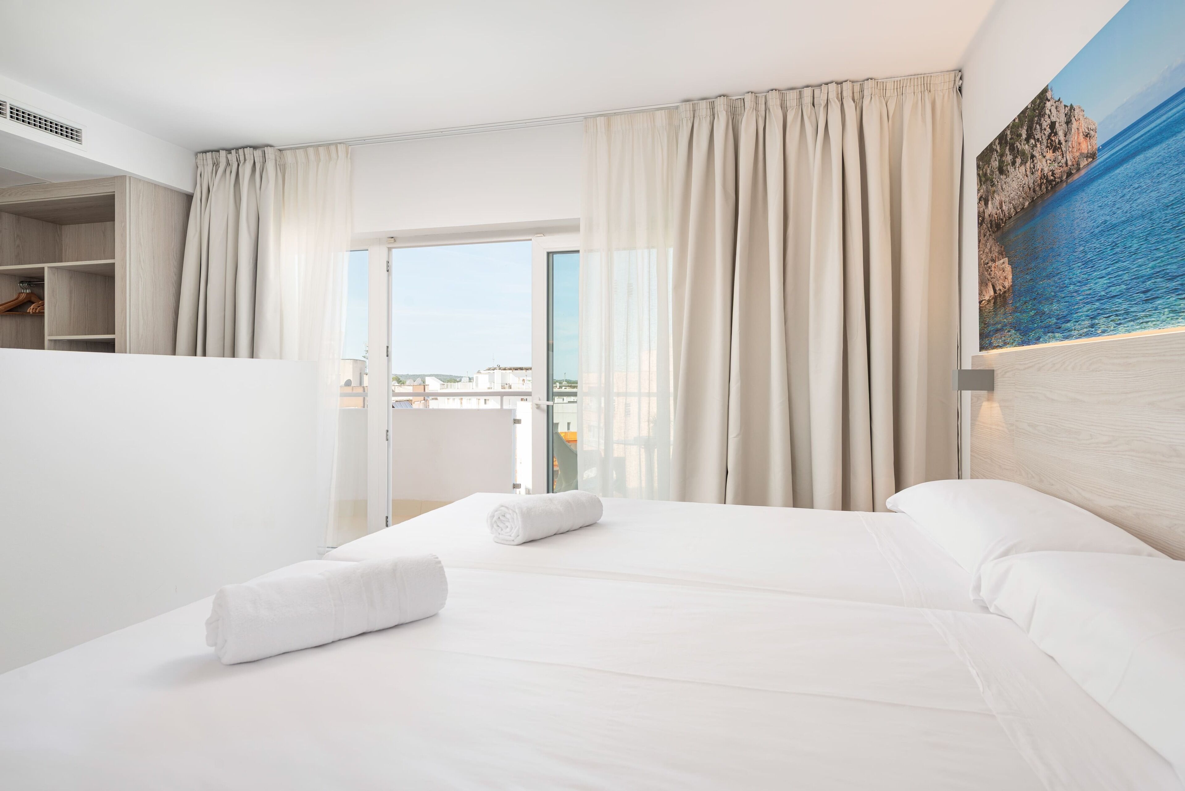 Habitación de hotel con cama, vista al mar y un cuadro en la pared.
