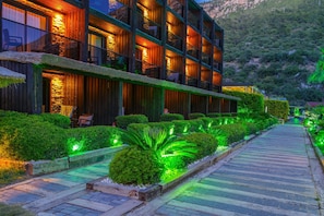 A modern hotel with multiple balconies, a well-lit pathway, and neatly trimmed hedges. - Manaspark Deluxe Hotel (Fethiye)