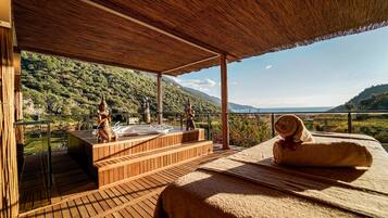 Eine Holzterrasse mit Whirlpool, einem Handtuch und einem herrlichen Bergblick.