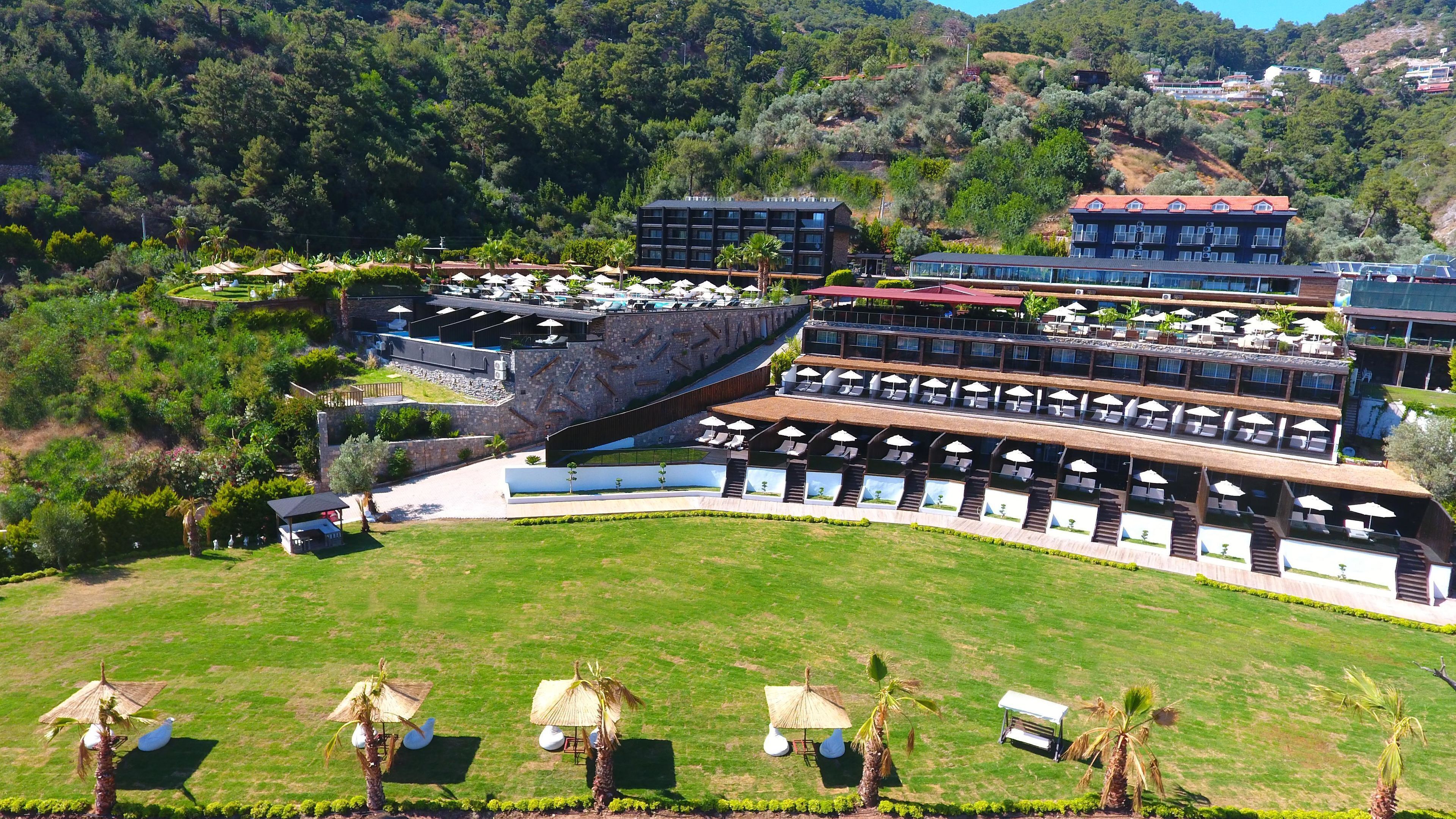 A resort with multiple levels of outdoor seating areas, a pool, and a view of the surrounding hills.