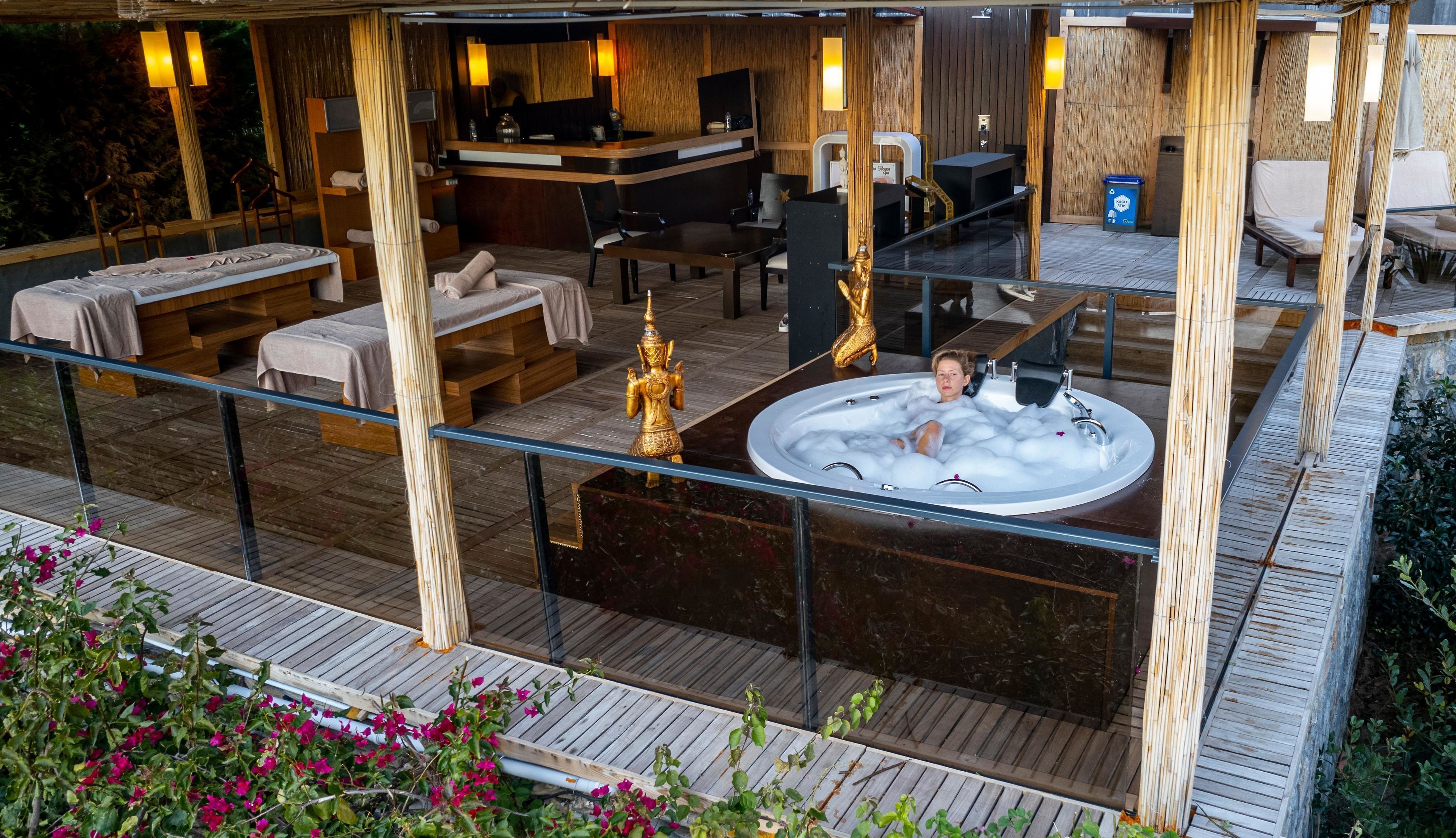 A spa area with a hot tub, wooden deck, and seating.
