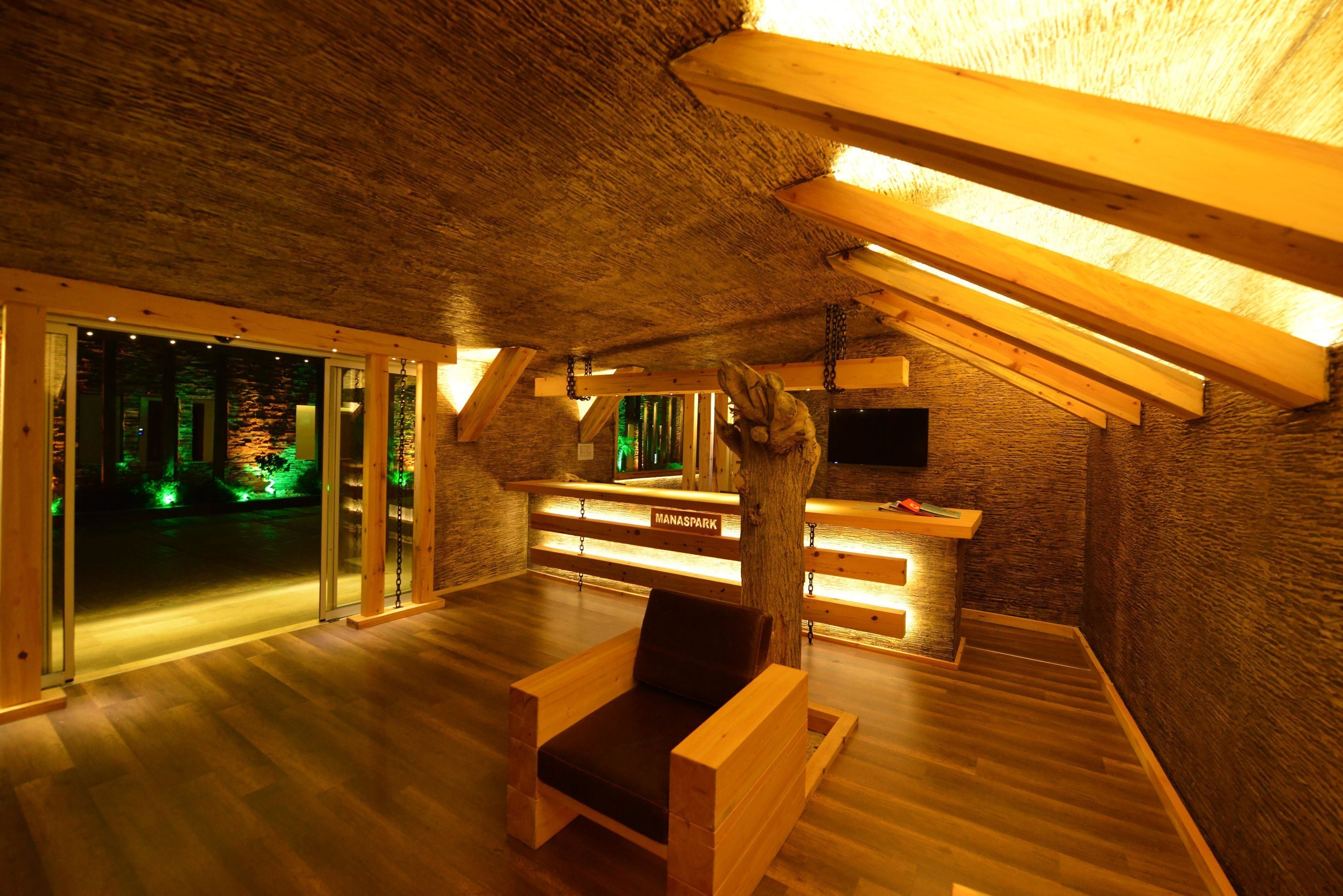 A cozy room with a wooden ceiling, a reception desk, and a large window overlooking a garden.