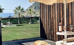 A terrace with a view of the sea, a table with wine glasses, and a hammock. - Manaspark Deluxe Hotel (Fethiye)