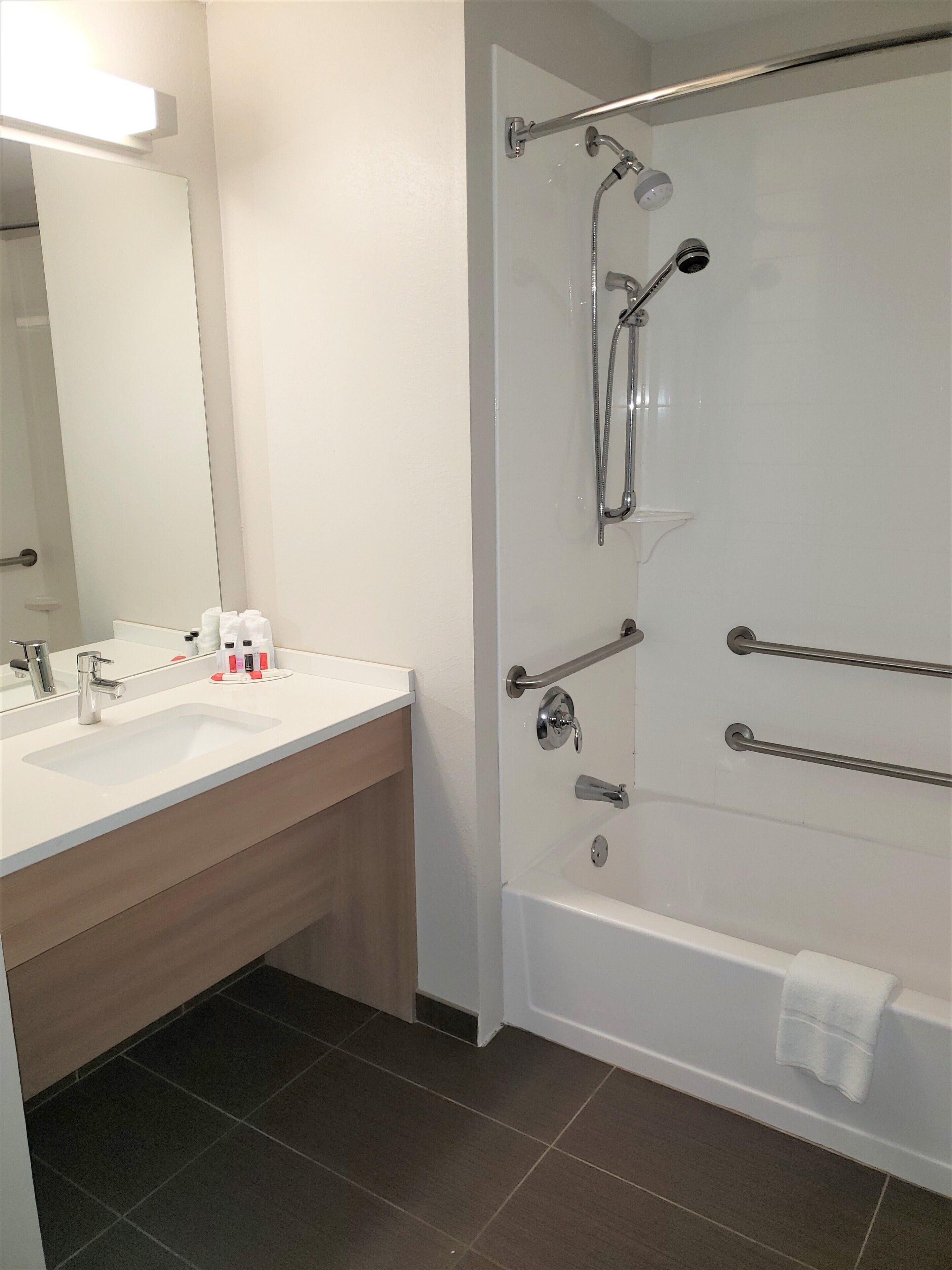 A modern bathroom with a white sink, mirror, and shower area.