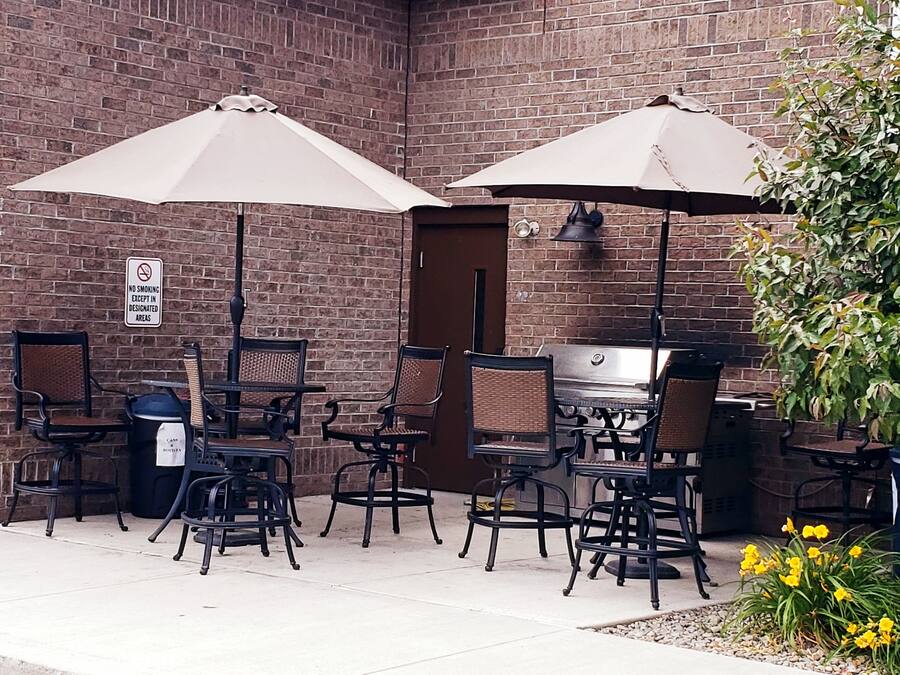 An outdoor seating area with brick walls, two large umbrellas, and wicker chairs.